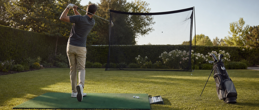 Golfer trainiert im Garten auf einer Matte vor einem sicher befestigten Schlagnetz