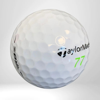 Weißer Golfball mit dimpled Oberfläche, Aufschrift und grüner Zahl 77 auf neutralem Hintergrund