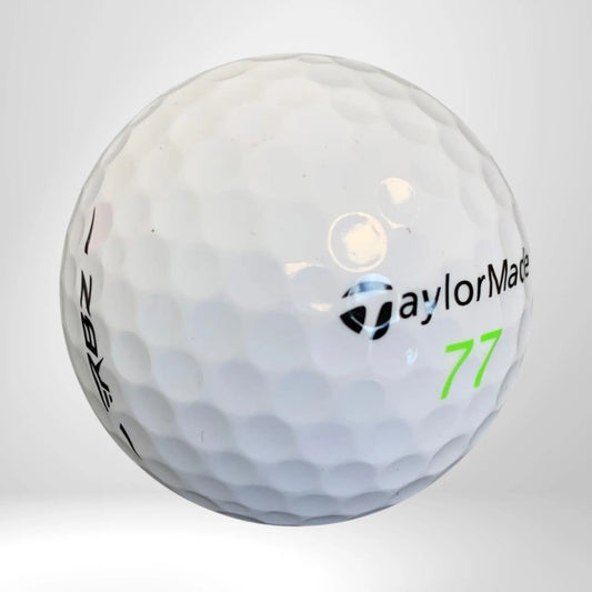 Weißer Golfball mit dimpled Oberfläche, Aufschrift und grüner Zahl 77 auf neutralem Hintergrund
