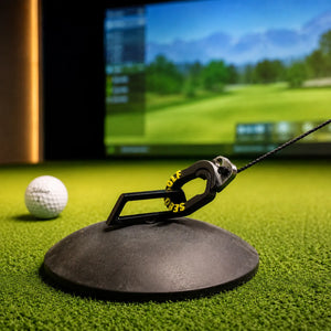 Sebo T Golf-Tee auf einem Indoor-Golfplatz mit Simulator im Hintergrund.