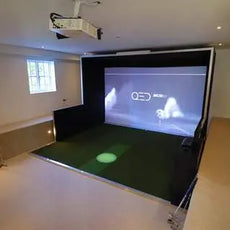 Moderner Indoor Golf Simulator mit Leinwand, Projektor und grünem Abschlagbereich in hellem Raum