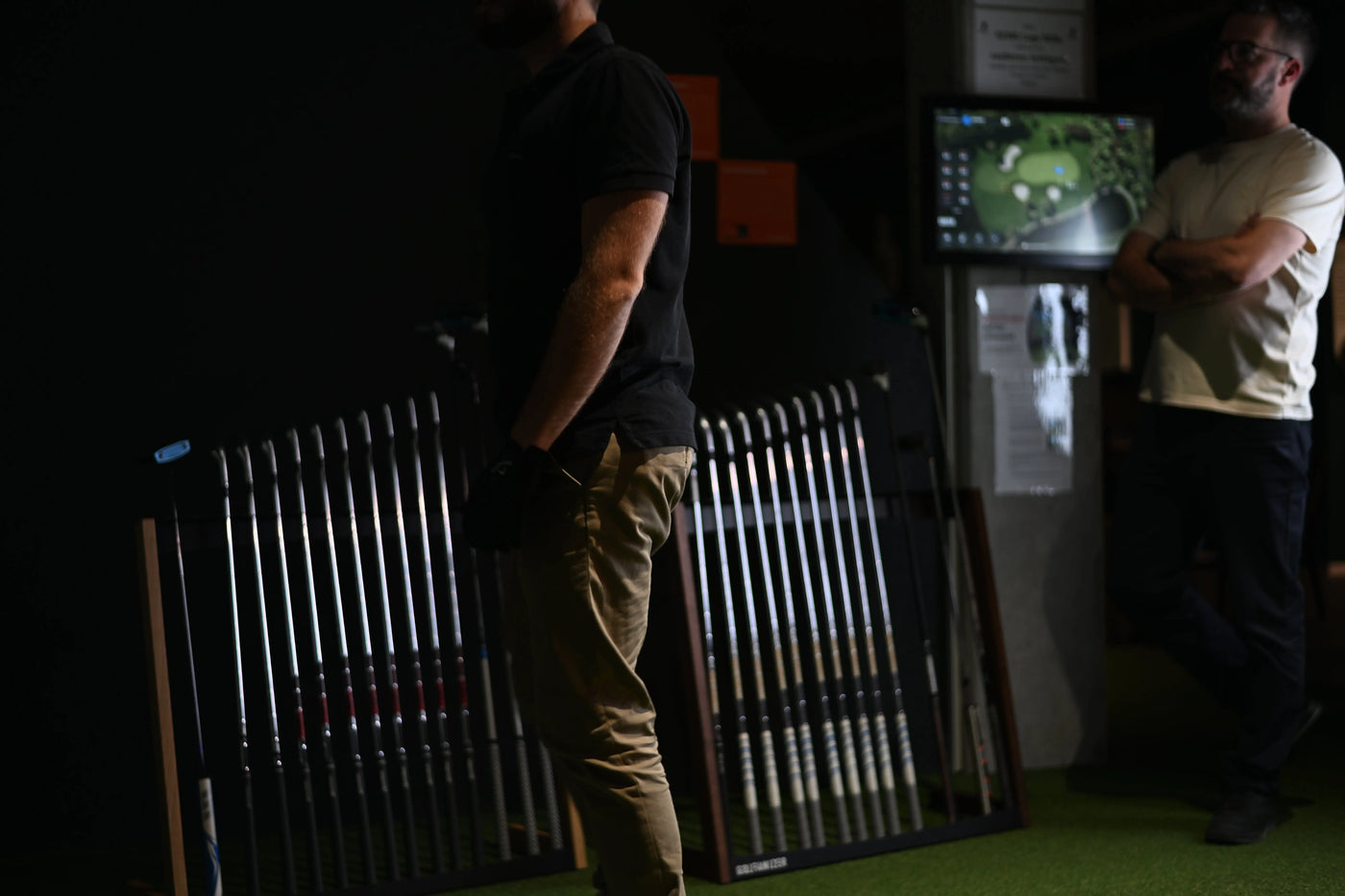 Golf Indoor Bereich mit schwarzem Eiche Golfschlägerständer, Golfschlägern und Bildschirm