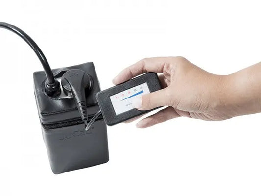 Hand hält JuCad Ladezustandsanzeige mit Magnetstecker an Akku für E-Trolley Golf Zubehör