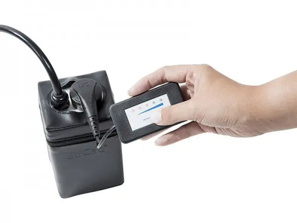 Hand hält JuCad Ladezustandsanzeige mit Magnetstecker an Akku für E-Trolley Golf Zubehör