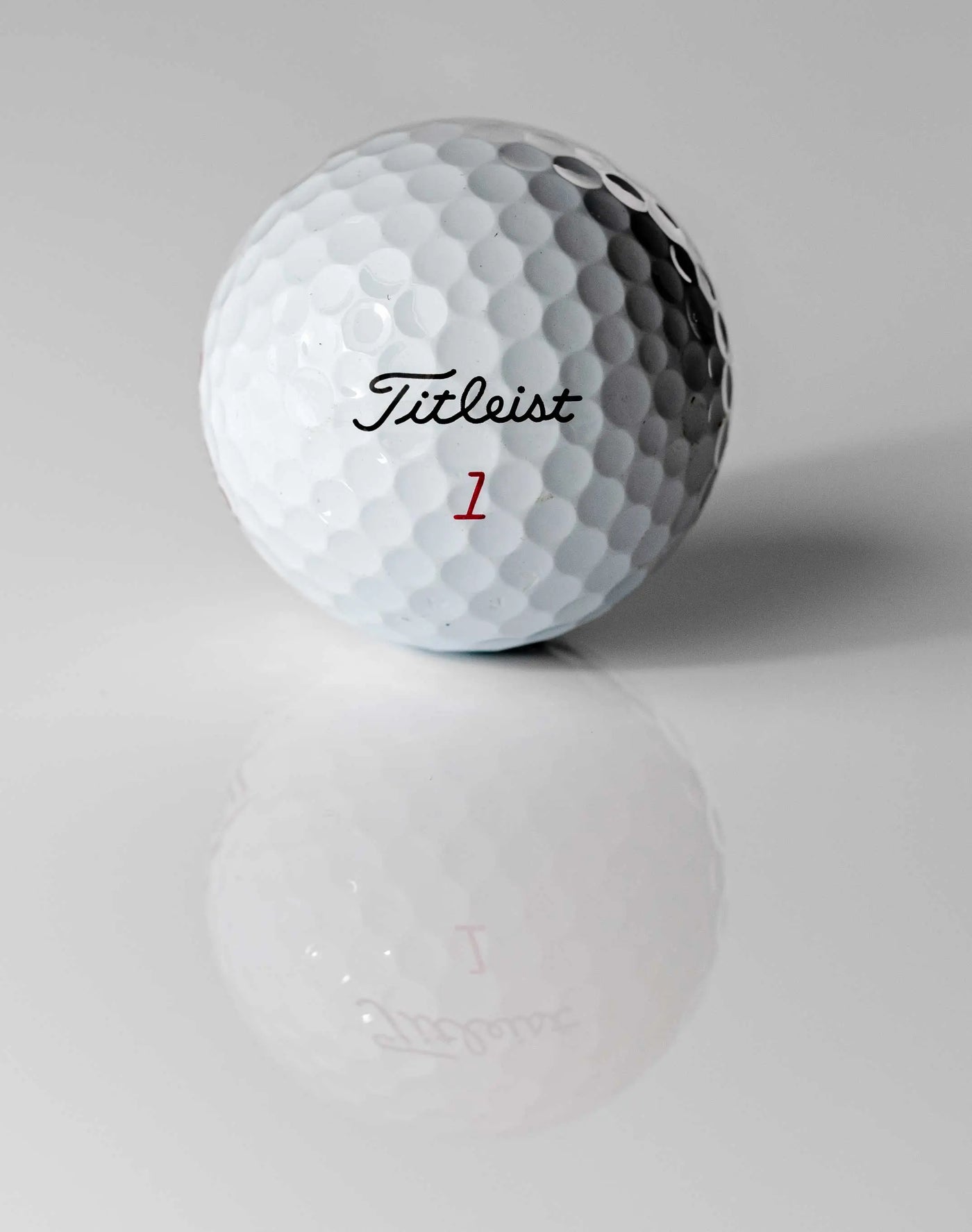 Weißer Golfball mit Dimples und Aufschrift, Nahaufnahme auf glänzender Oberfläche