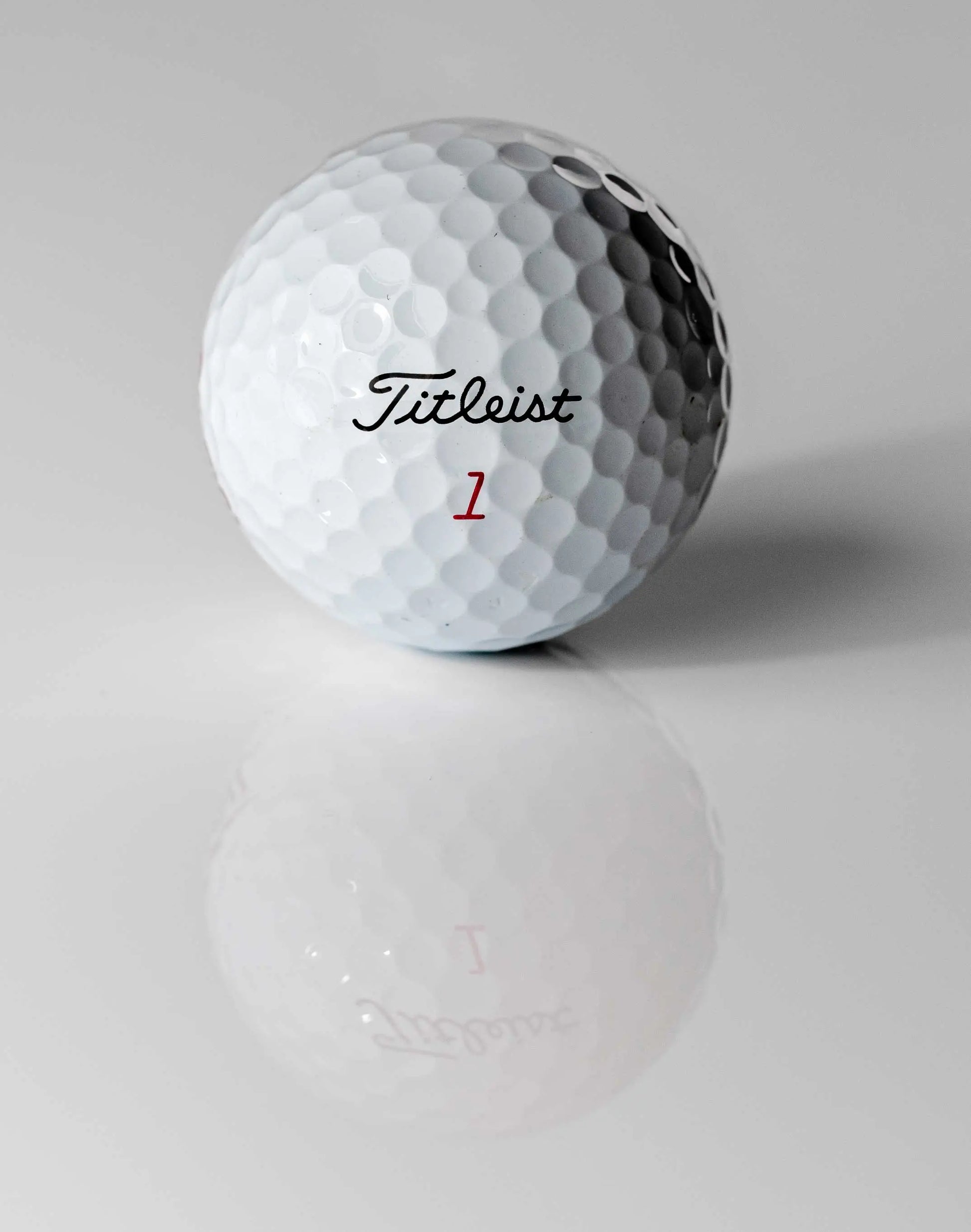 Weißer Golfball mit Dimples und Aufschrift, Nahaufnahme auf glänzender Oberfläche